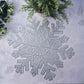 Silver metallic snowflake placemat on a light surface.