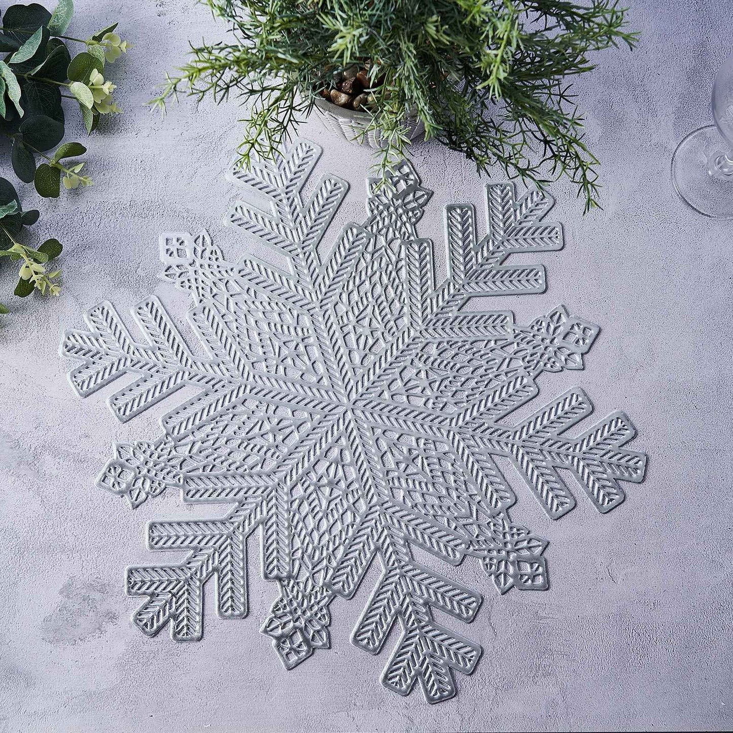 Silver metallic snowflake placemat on a light surface.