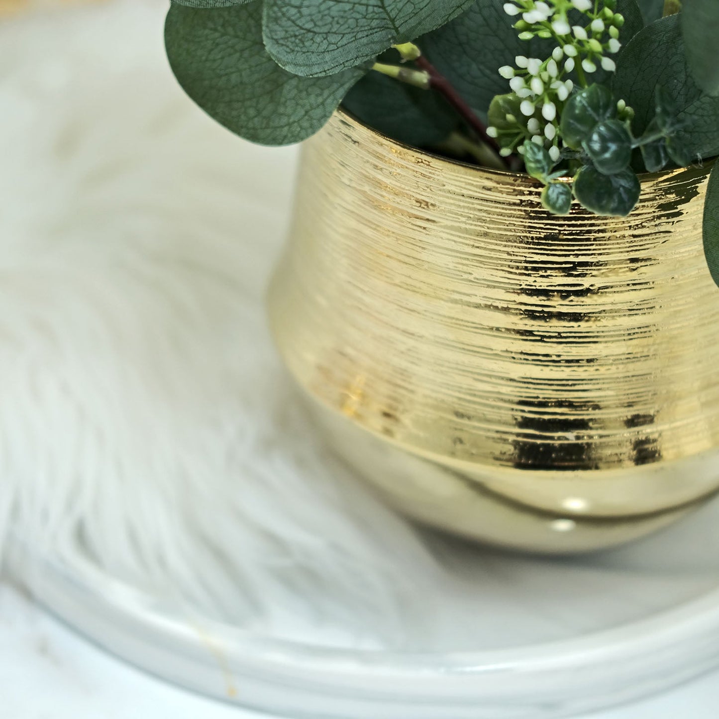 Gold textured round ceramic flower pot with greenery.