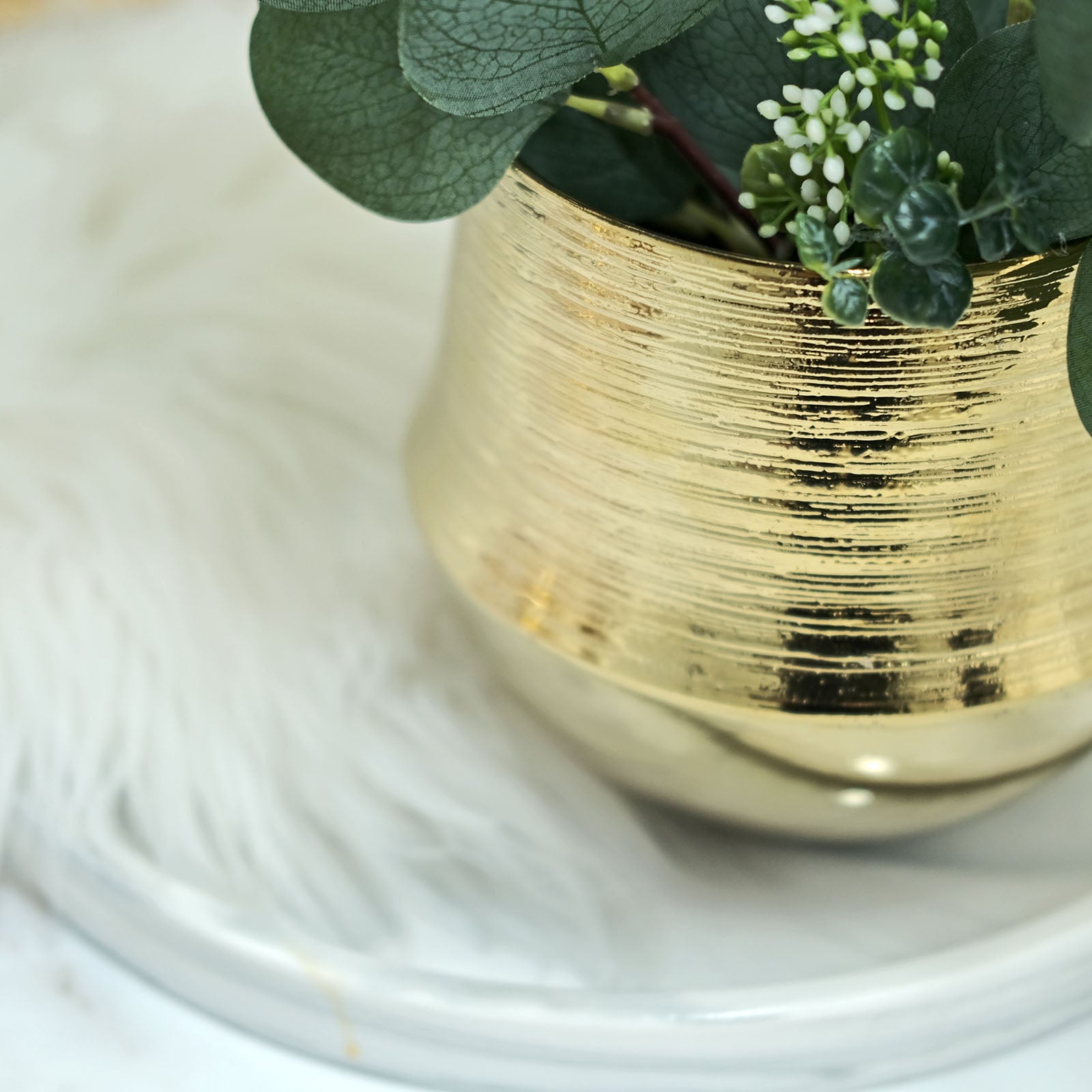 Gold textured round ceramic flower pot with greenery.