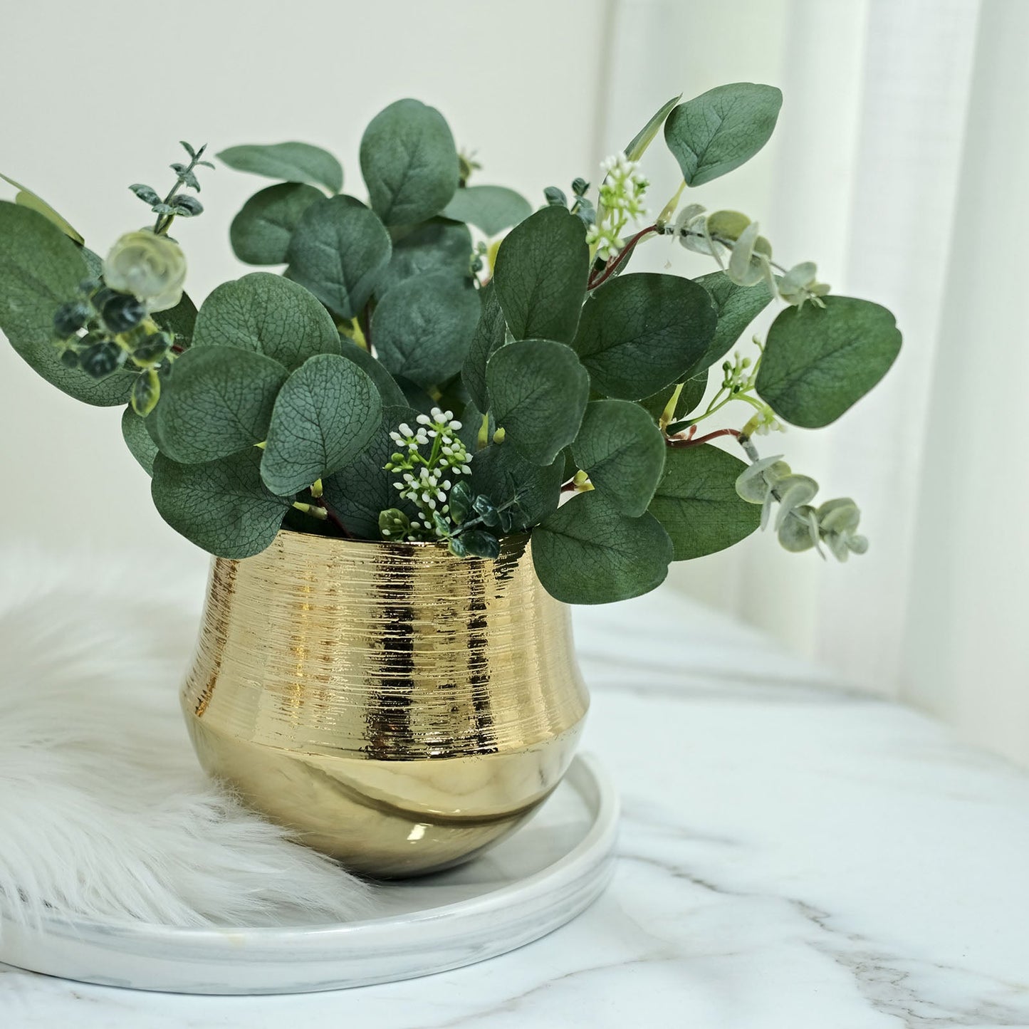 Gold textured round ceramic flower pot with greenery.
