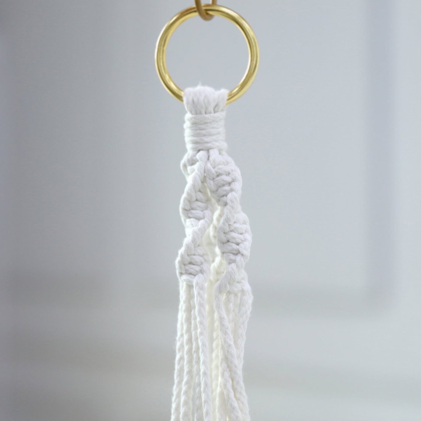 Ivory macrame hanging planter basket with tassel for boho chic decor.