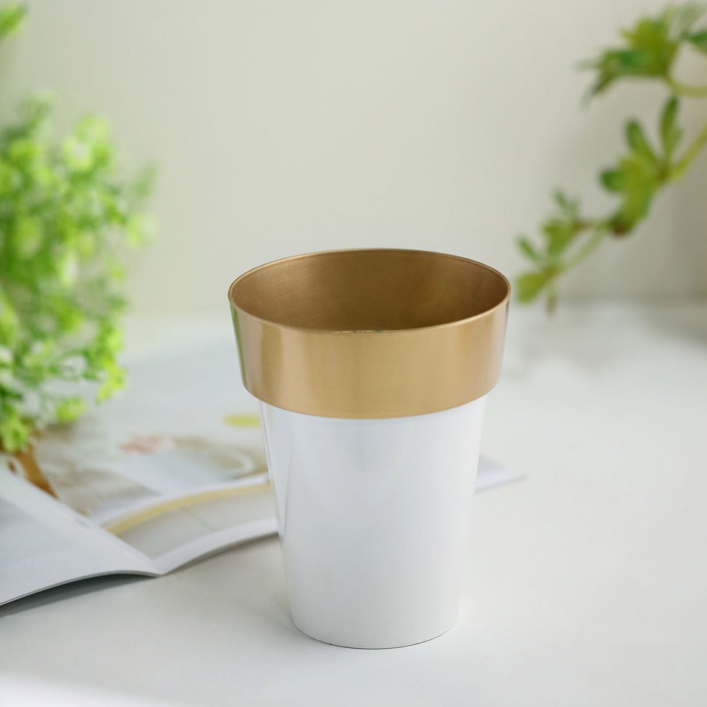 White gold rimmed medium flower plant pot on a table.