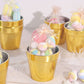 Gold mini party favor buckets filled with colorful treats.