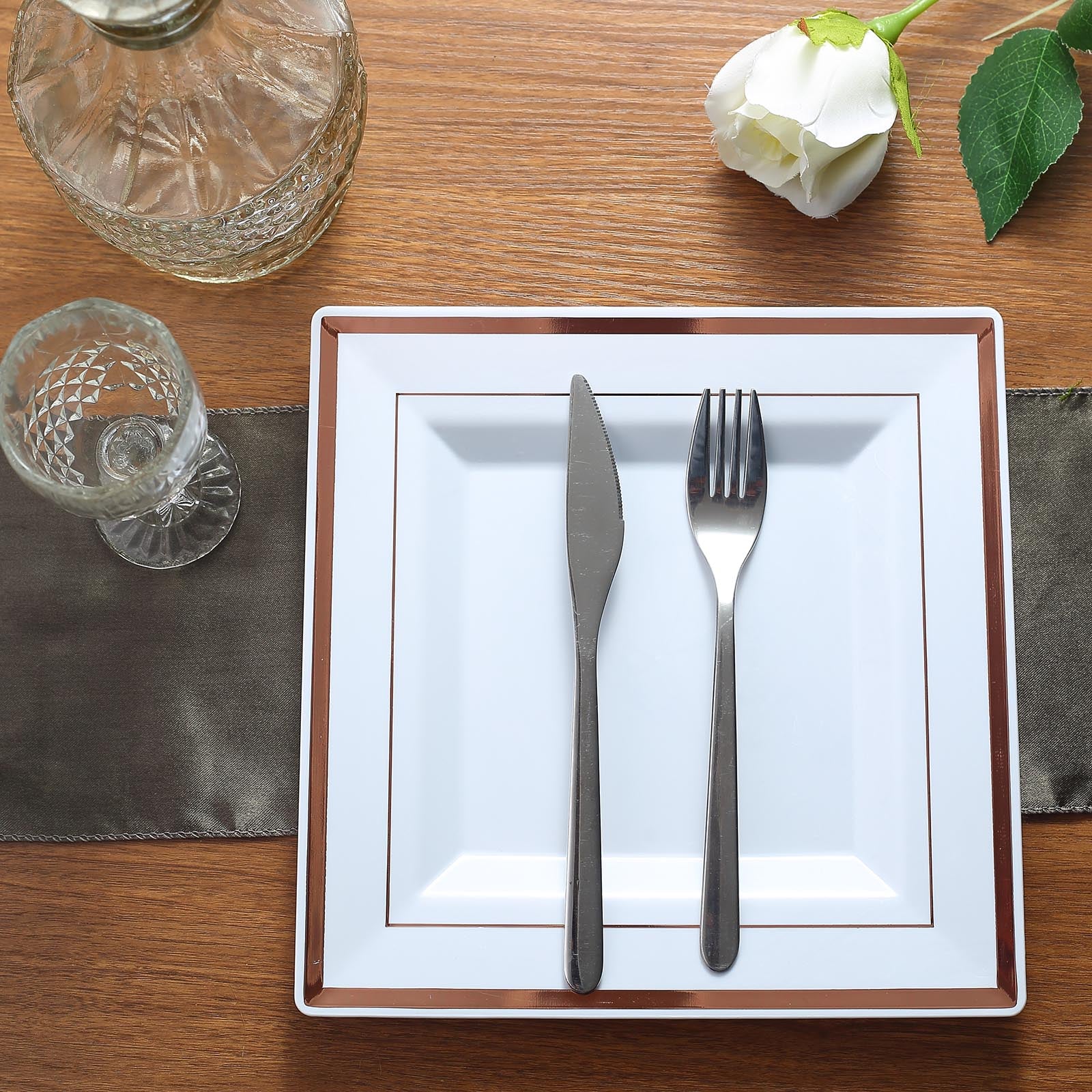 Rose gold trim white square plastic dinner plate with cutlery.