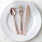 Metallic rose gold disposable cutlery set on a white plate.