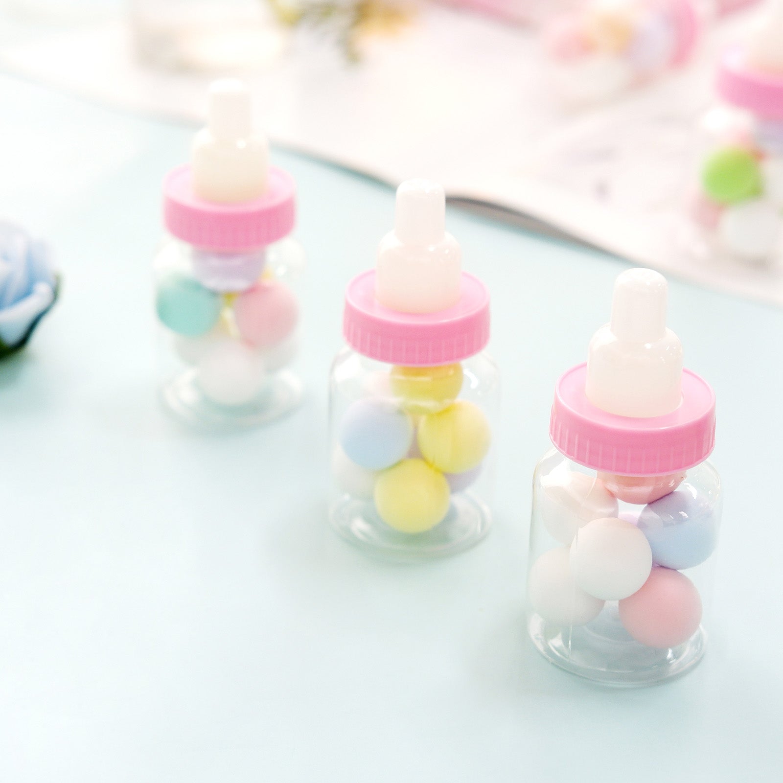 3.5" pink baby bottles filled with colorful candies, perfect for party favors.