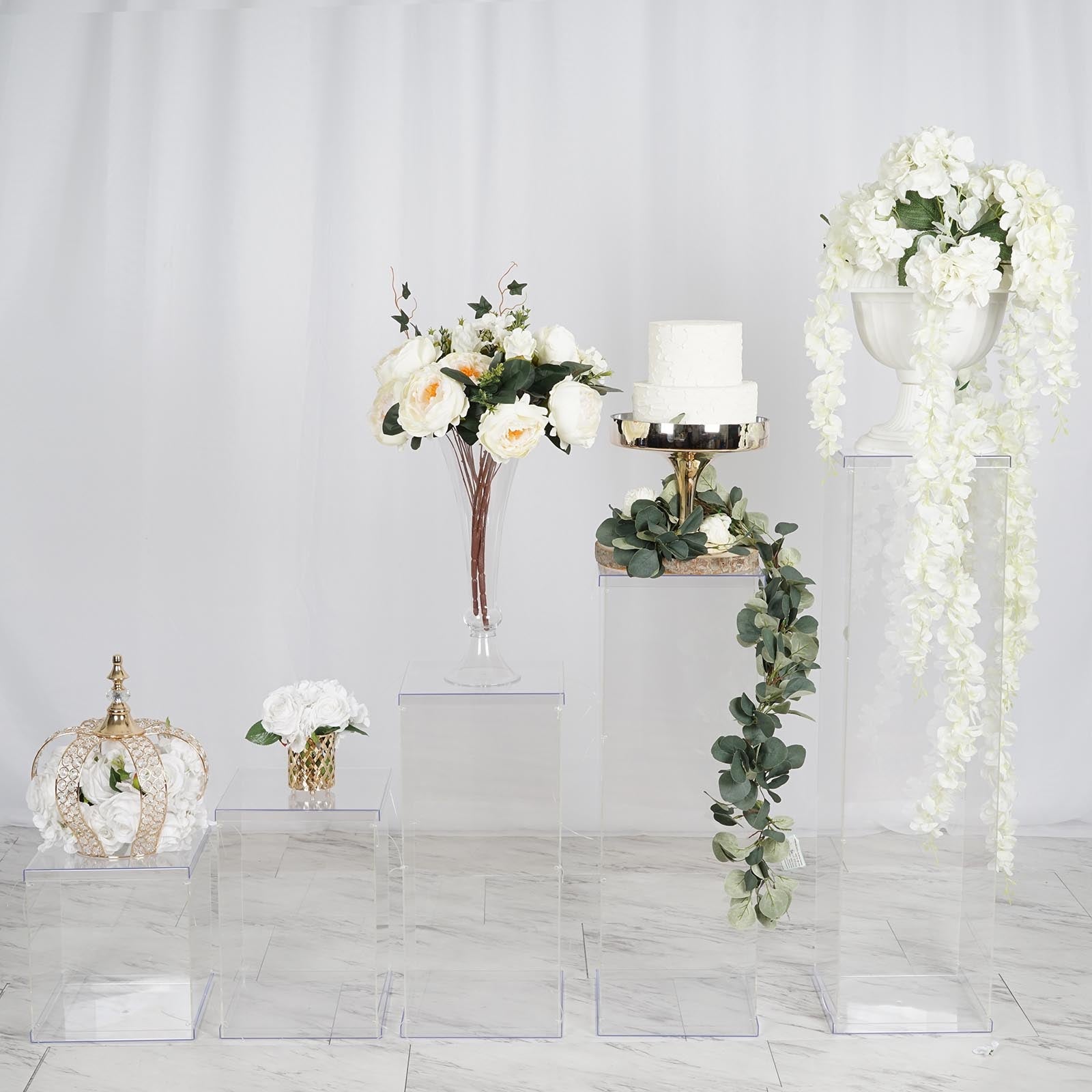 Clear acrylic pedestal risers for display with floral arrangements and decor.