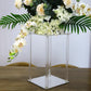 Clear acrylic wedding centerpiece vase with flowers and greenery.