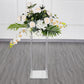 Clear acrylic wedding centerpiece vase with flowers on a square mirror base.