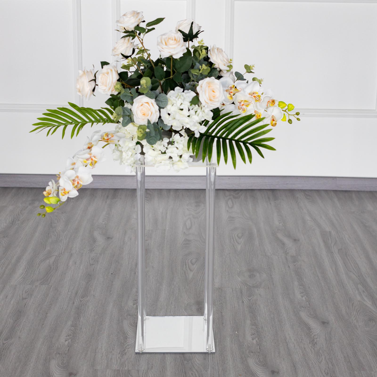 Clear acrylic wedding centerpiece vase with flowers on a square mirror base.