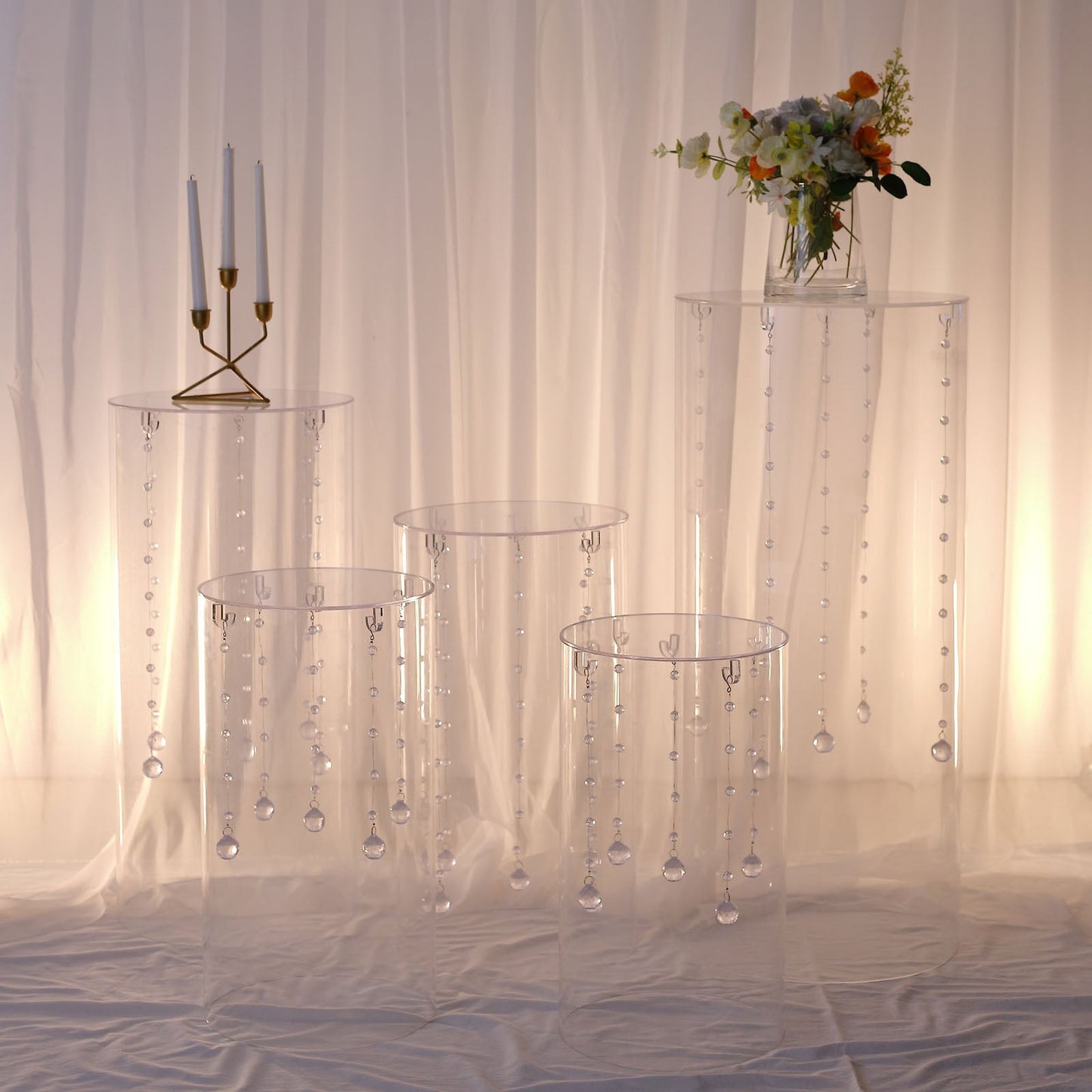 Clear acrylic pedestal stands with hanging hooks for wedding display.