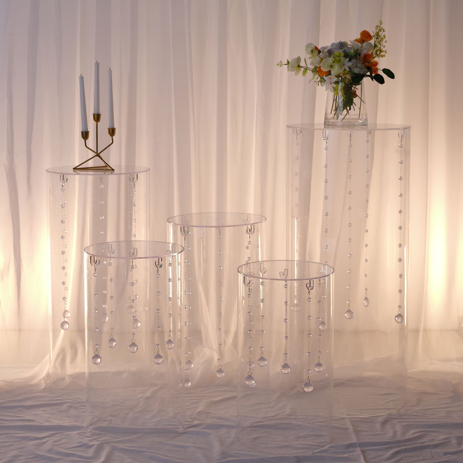 Clear acrylic pedestal stands with hanging hooks for wedding display.