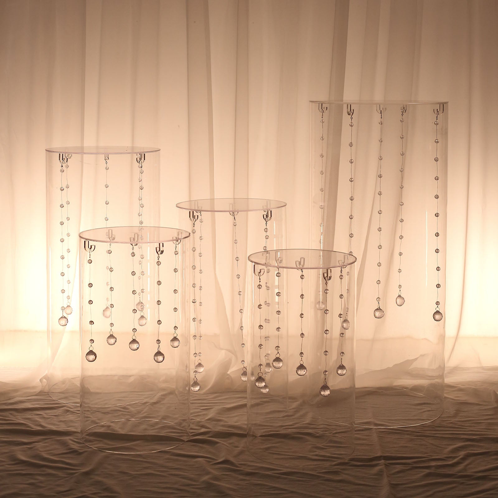 Clear acrylic pedestal stands with hanging hooks for cake display.