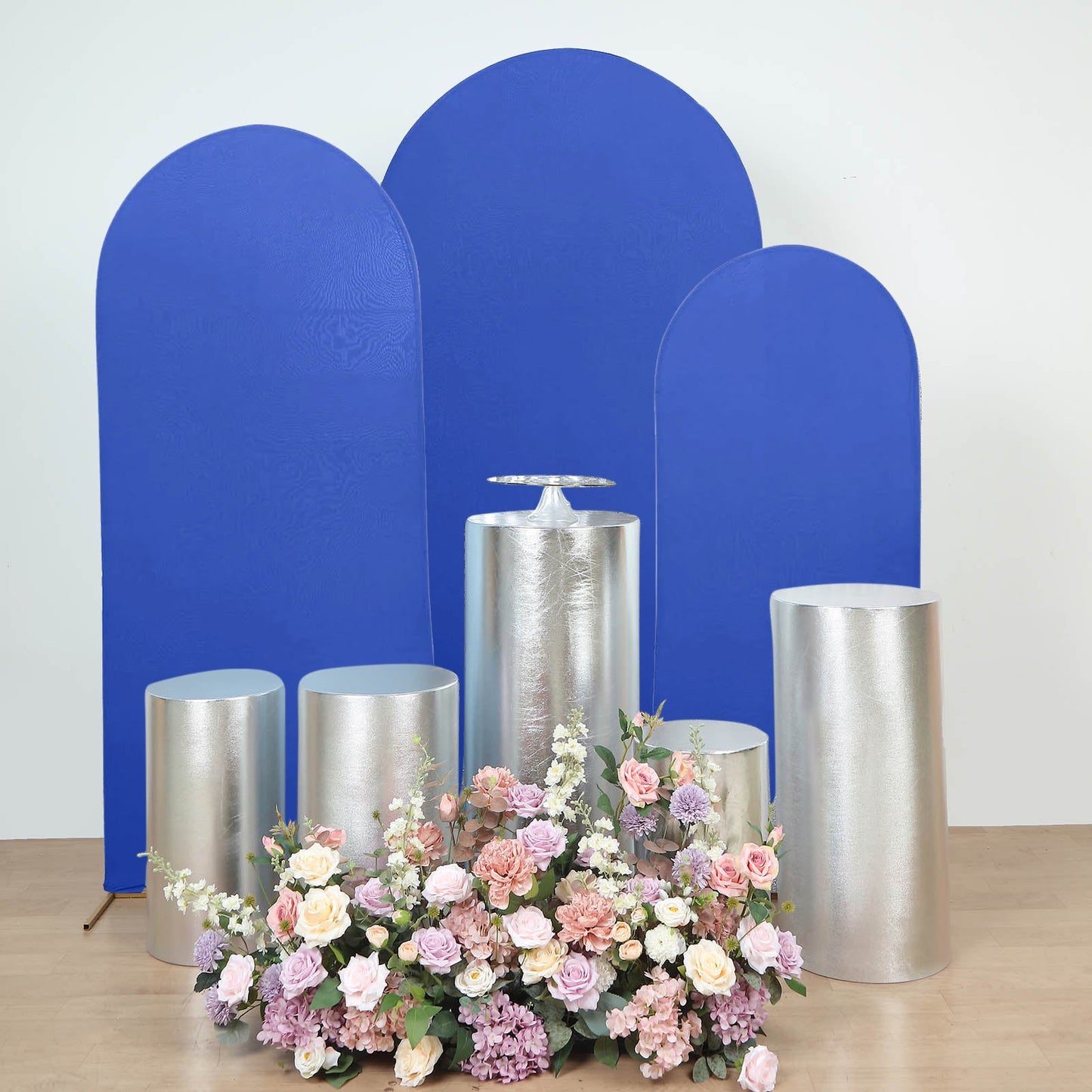 Metallic silver spandex pedestal stand covers with floral arrangement.