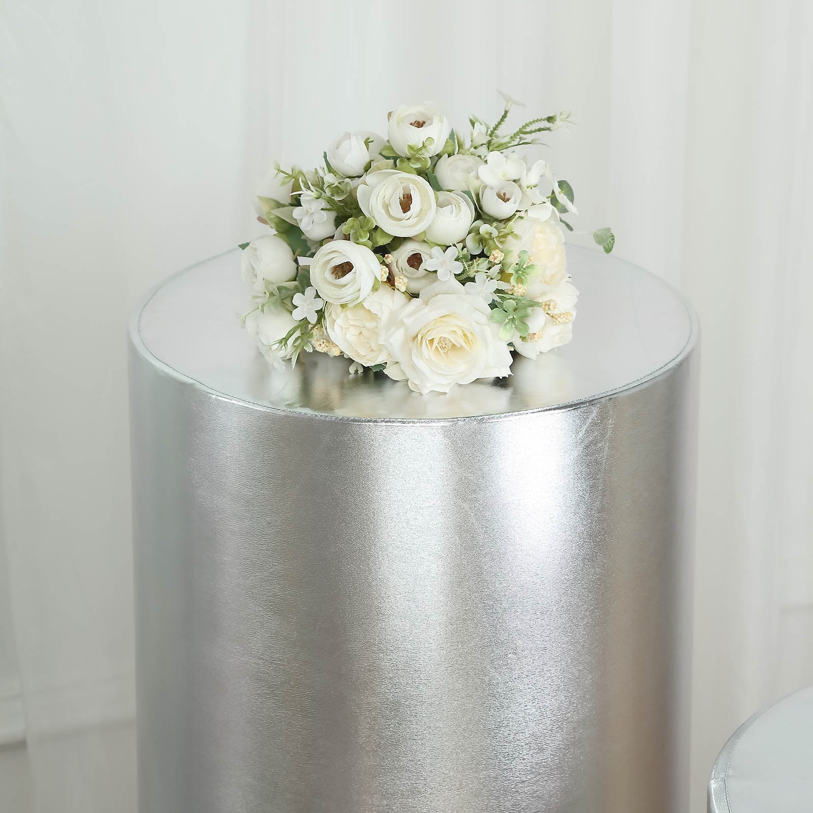 Metallic silver spandex pedestal stand cover with floral arrangement.