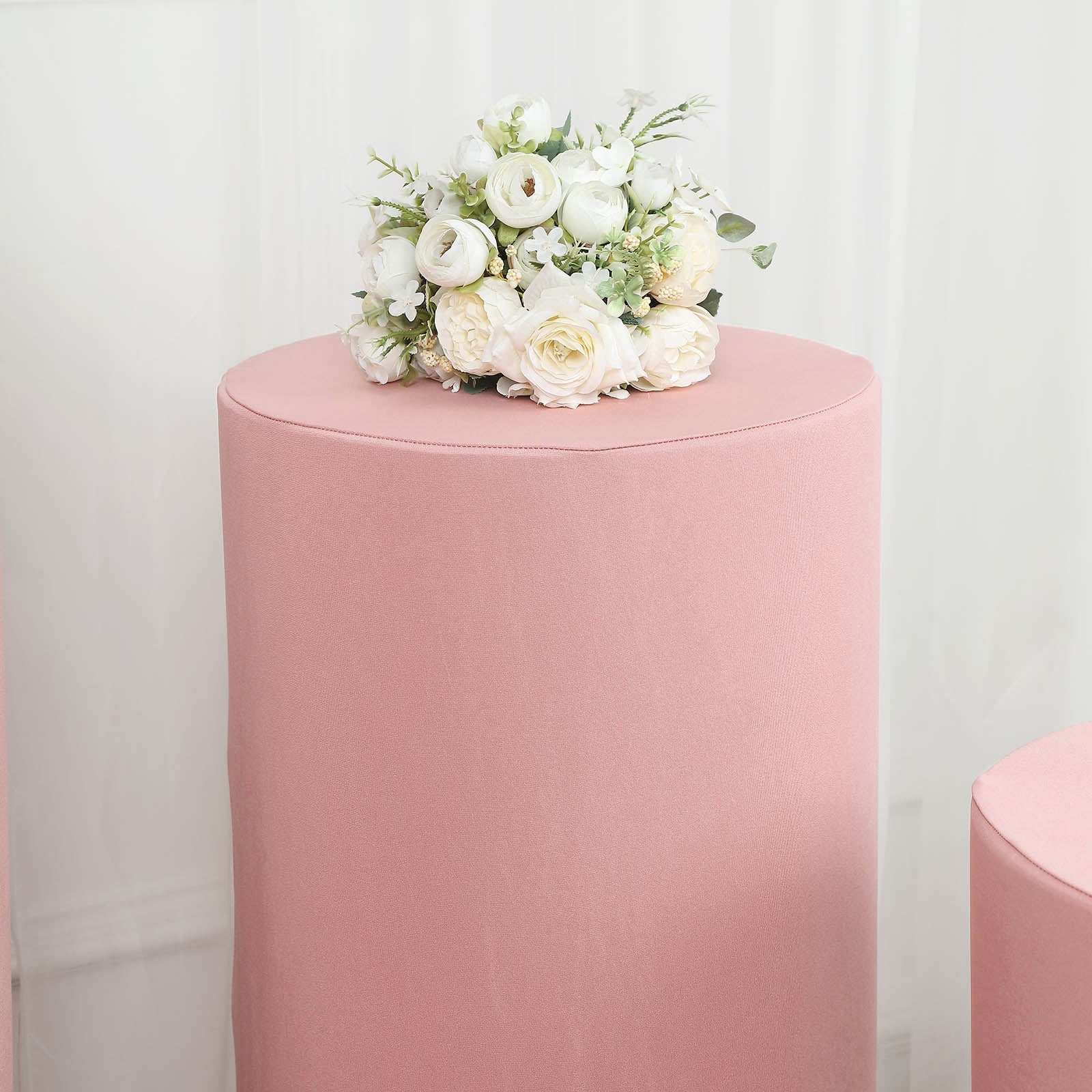Dusty rose spandex pedestal stand cover with floral arrangement.