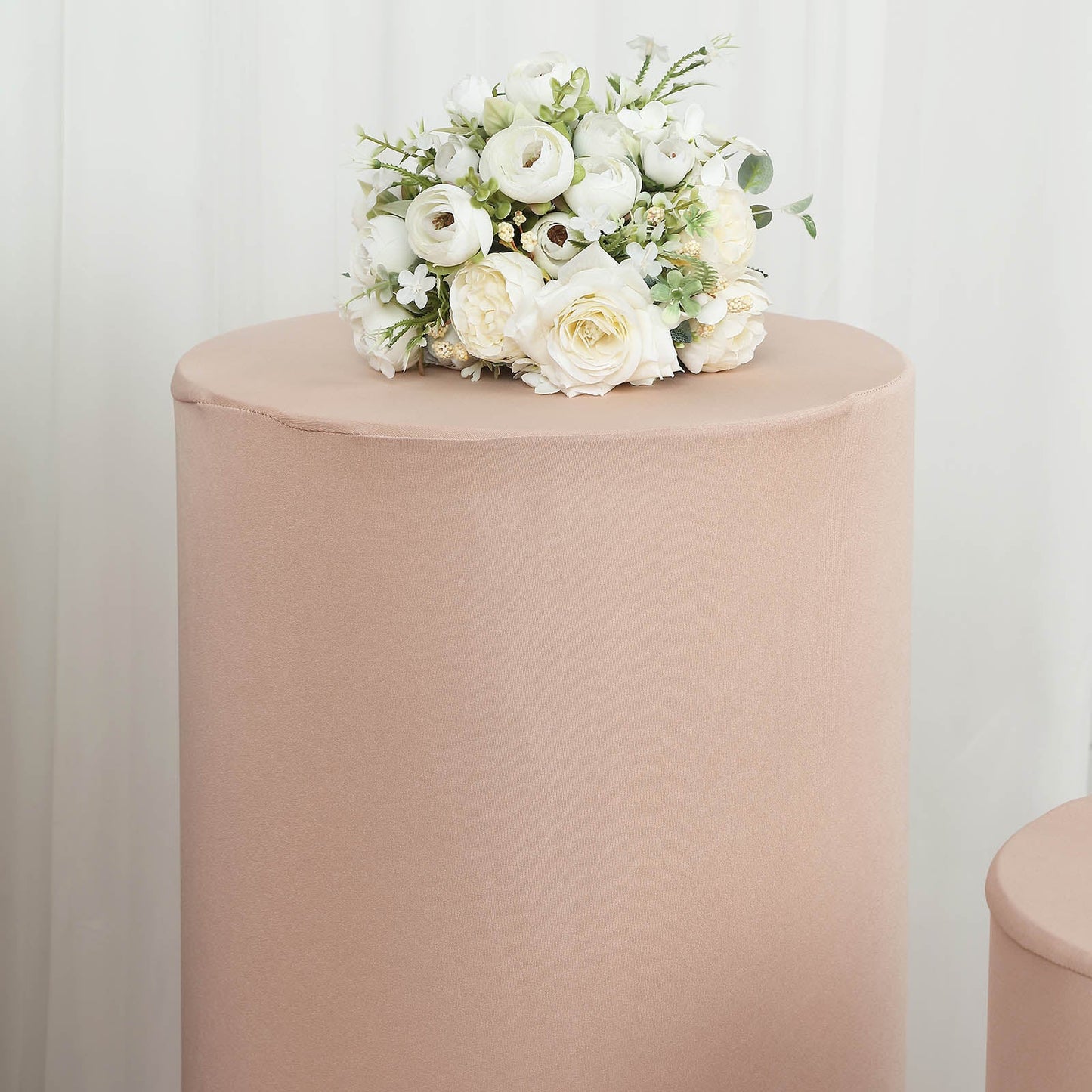 Nude spandex pedestal stand cover with floral arrangement on top.