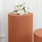 Rust spandex cylinder pedestal stand cover with flowers on top.