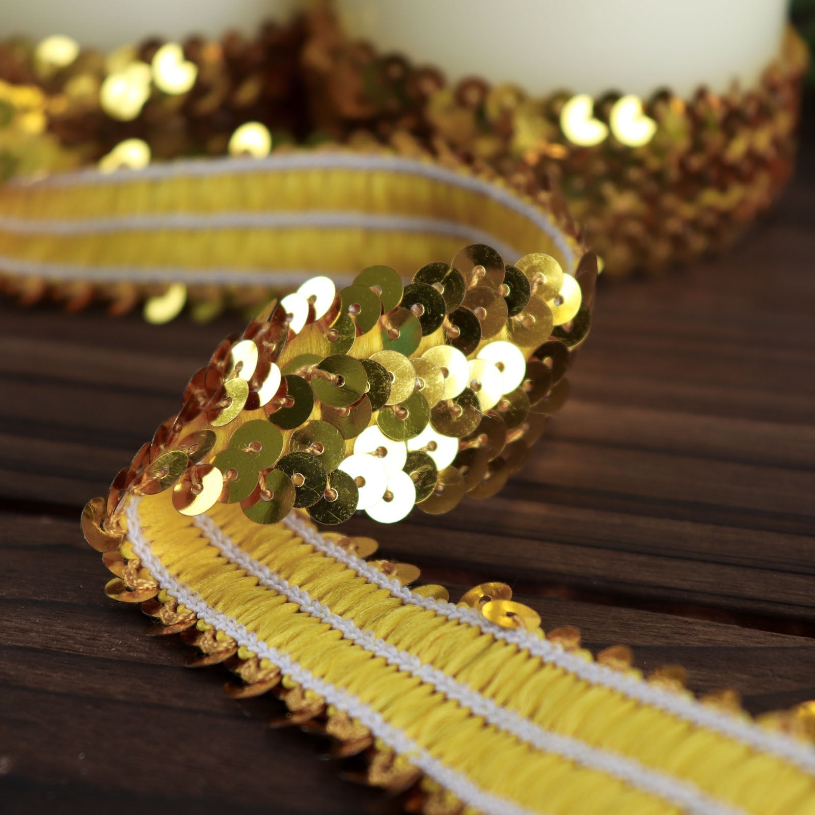 Metallic gold sequin stretch fabric ribbon on a wooden surface.