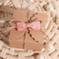 Dusty rose grosgrain pre-tied ribbon bow on a gift box.
