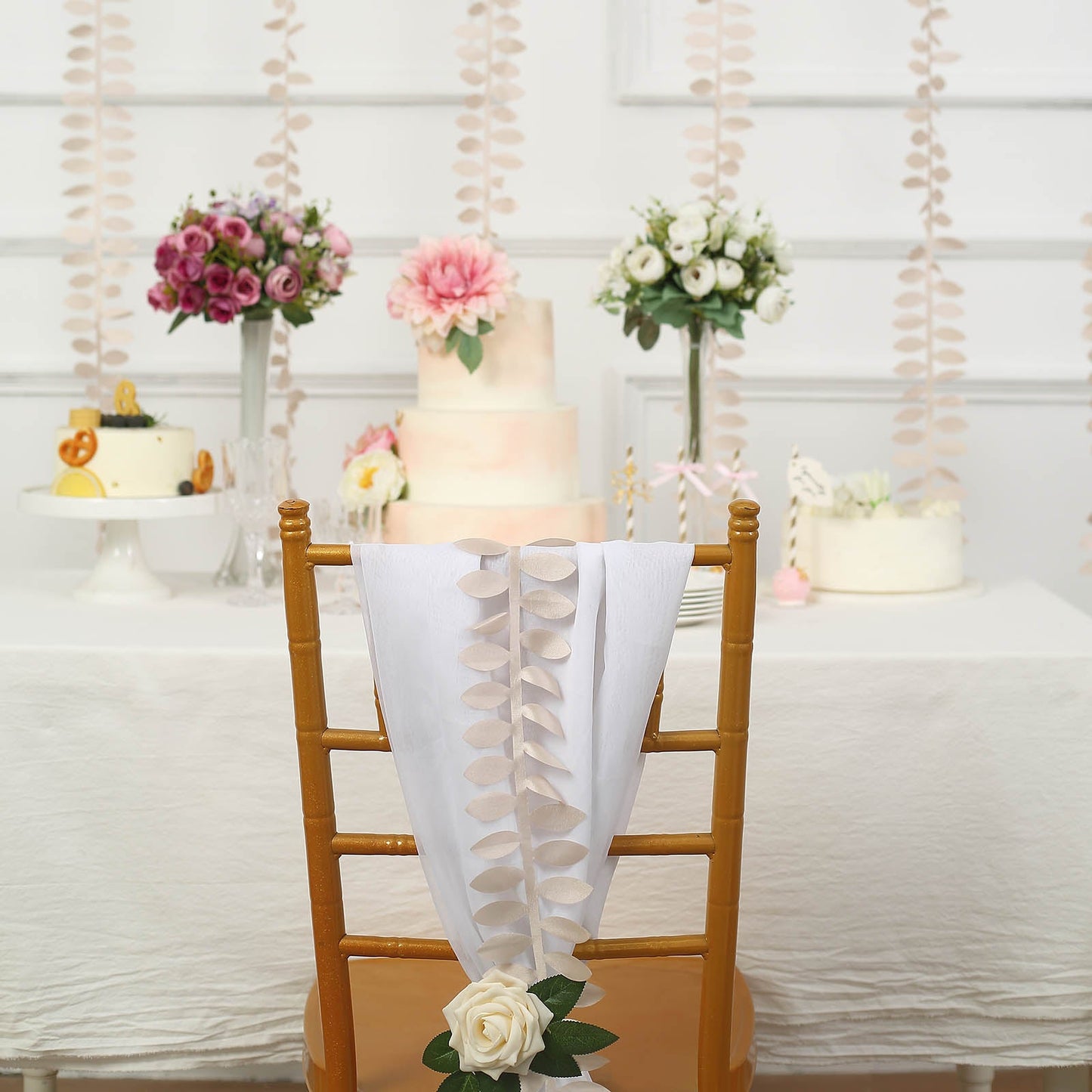 Beige leaf petal taffeta ribbon sash on a decorated chair at an event.