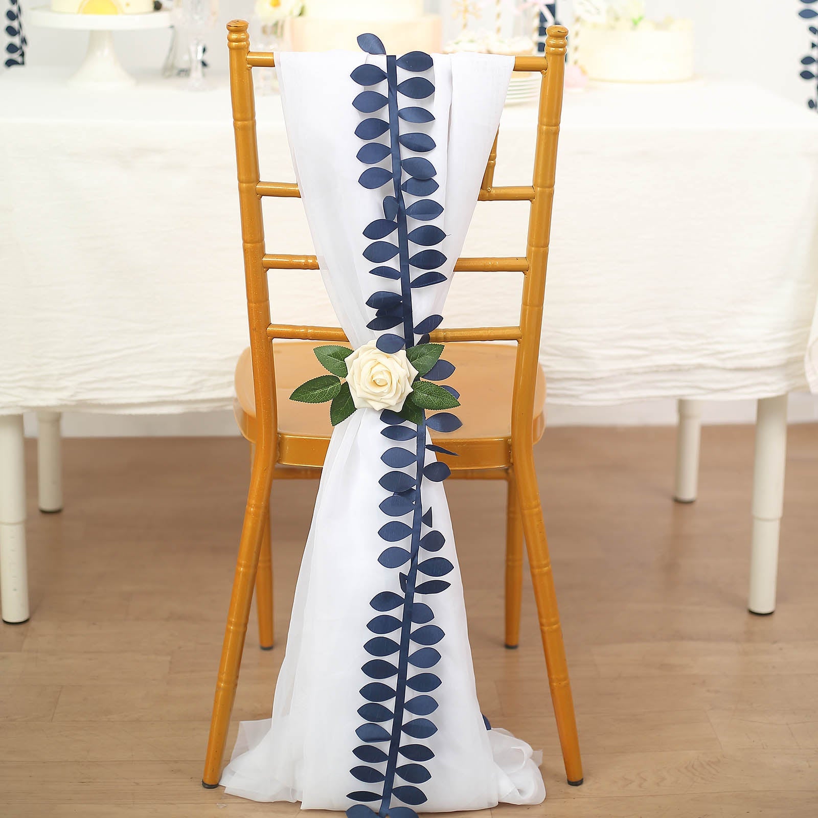 Navy blue leaf petal taffeta ribbon sash on a chair with a flower decoration.