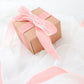 Dusty rose velvet ribbon spool on a gift box with tulle fabric.