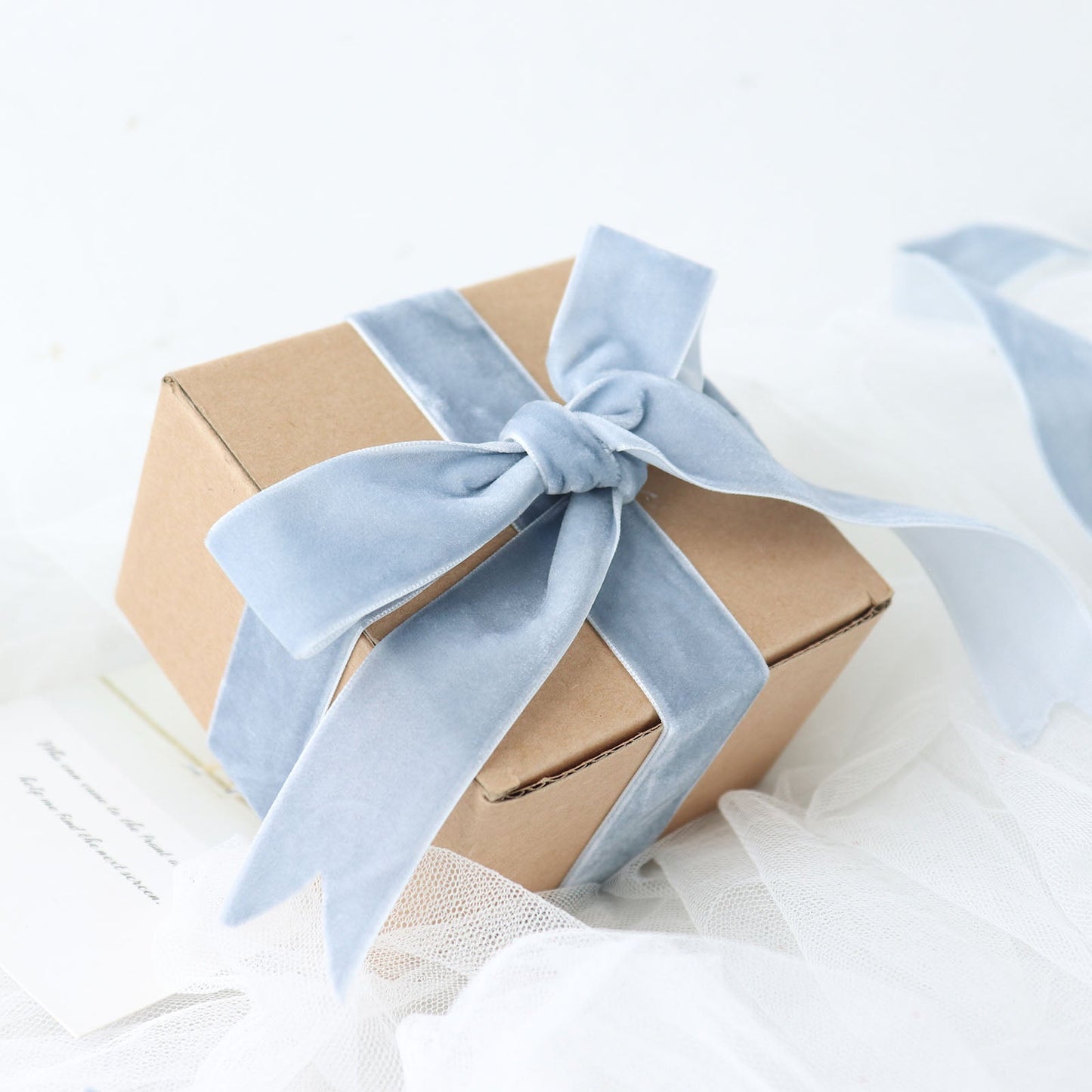 Dusty blue velvet ribbon tied around a gift box.