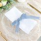 Dusty blue velvet ribbon on a white napkin, styled for a table setting.