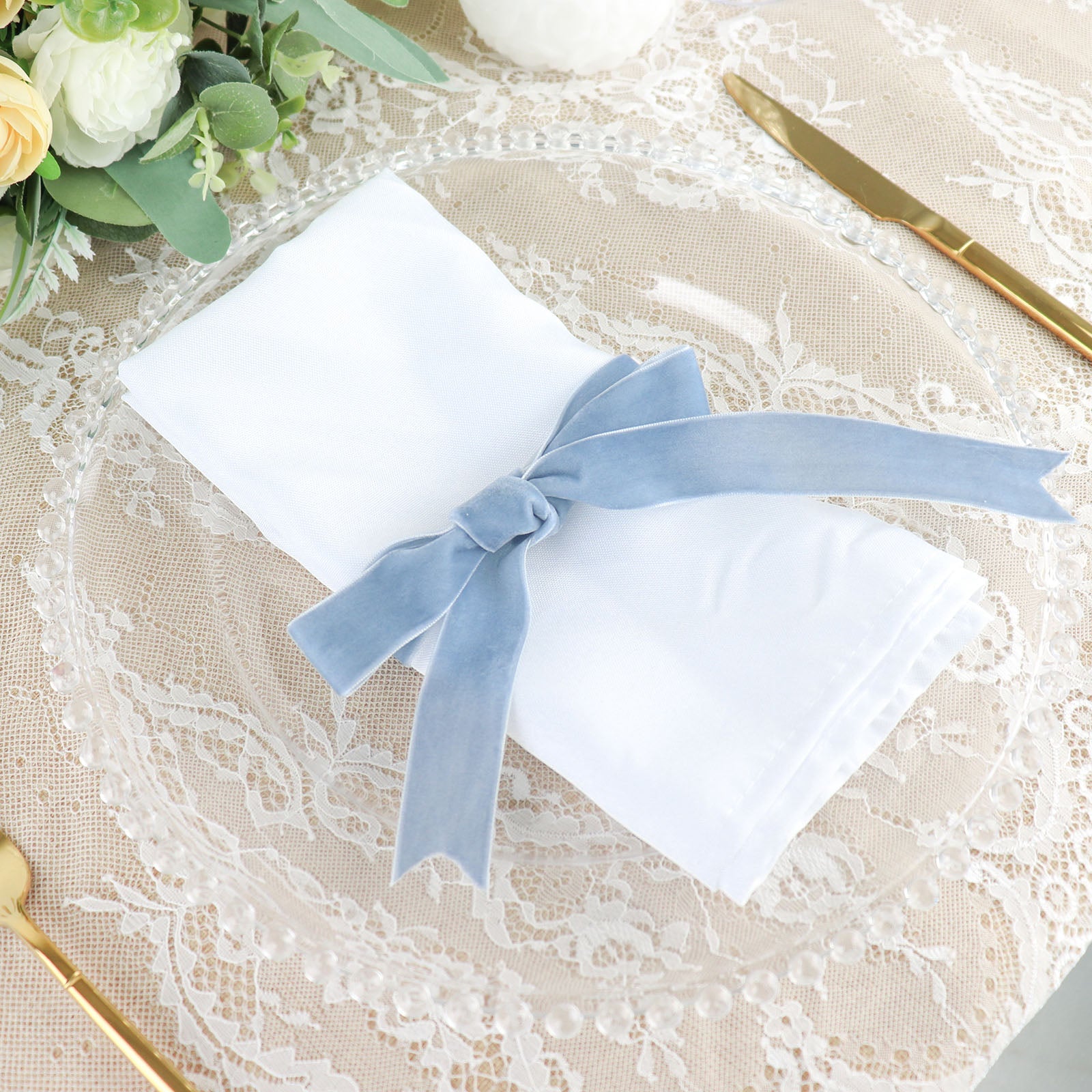 Dusty blue velvet ribbon on a white napkin, styled for a table setting.