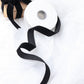 Black velvet ribbon spool on white fabric background.