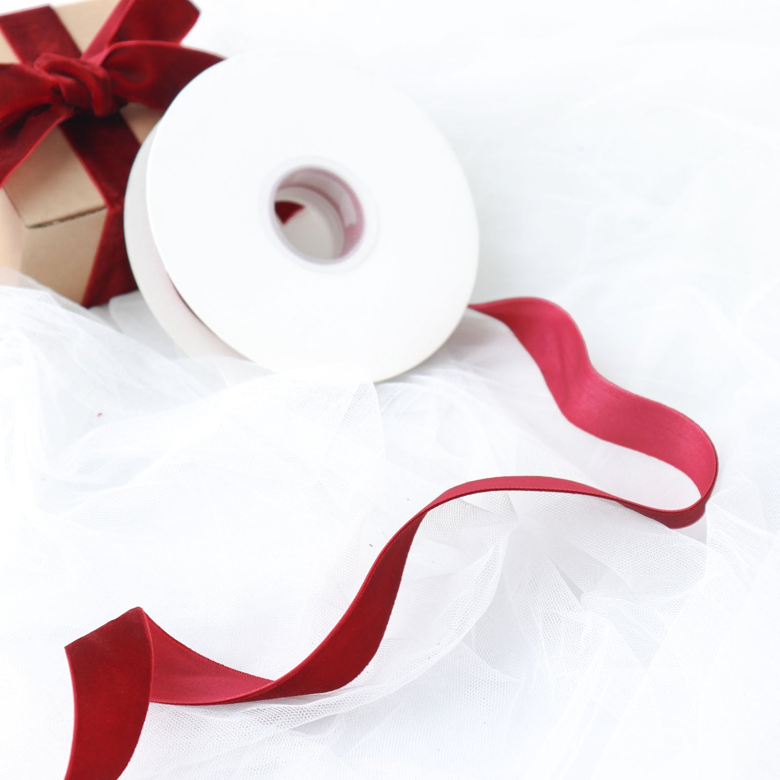 Burgundy velvet ribbon spool on white fabric background