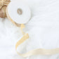 Champagne velvet ribbon spool on white fabric background.