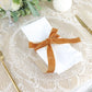 Gold velvet ribbon tied around a white napkin on a decorative plate.