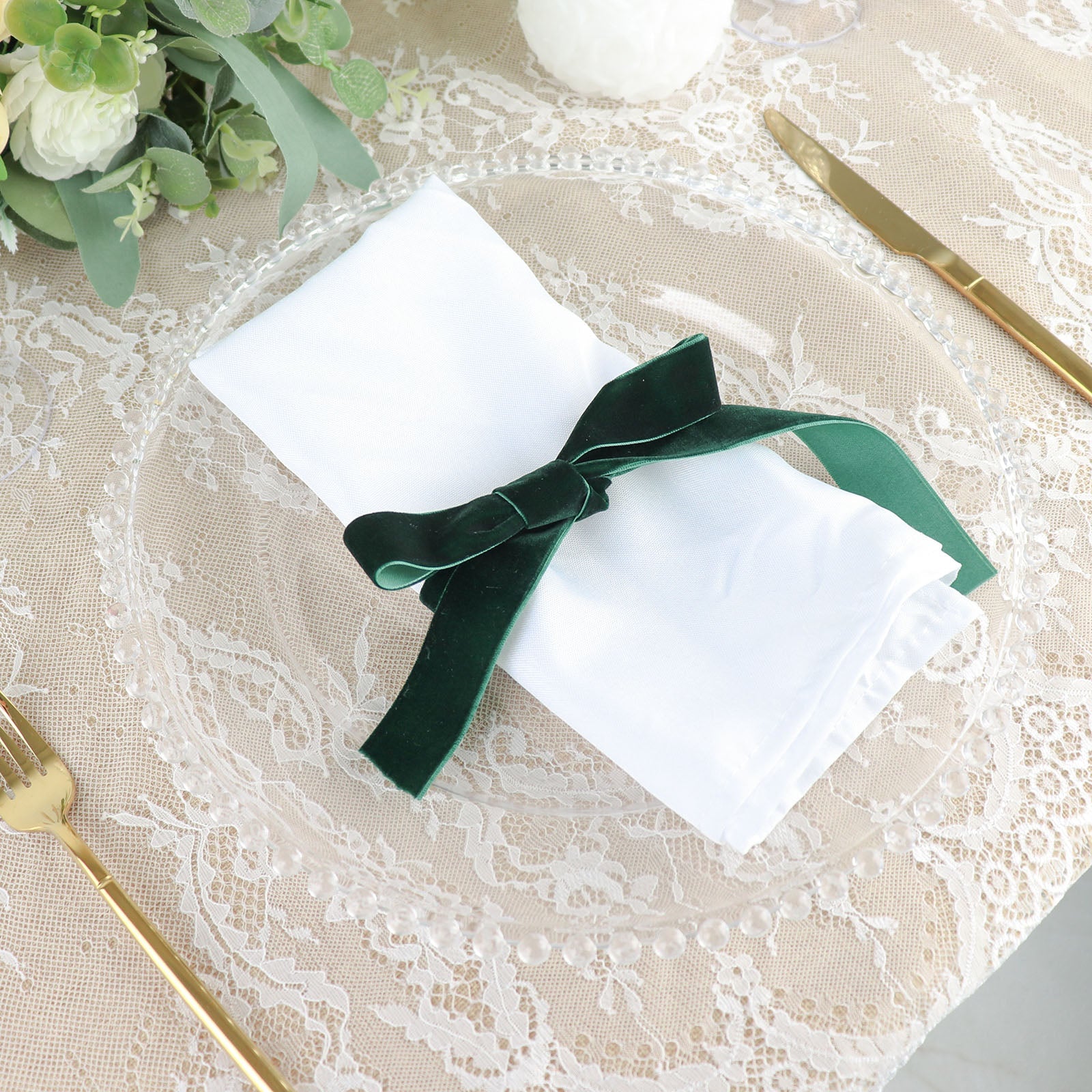 Hunter emerald green velvet ribbon on a white napkin at a dinner setting.