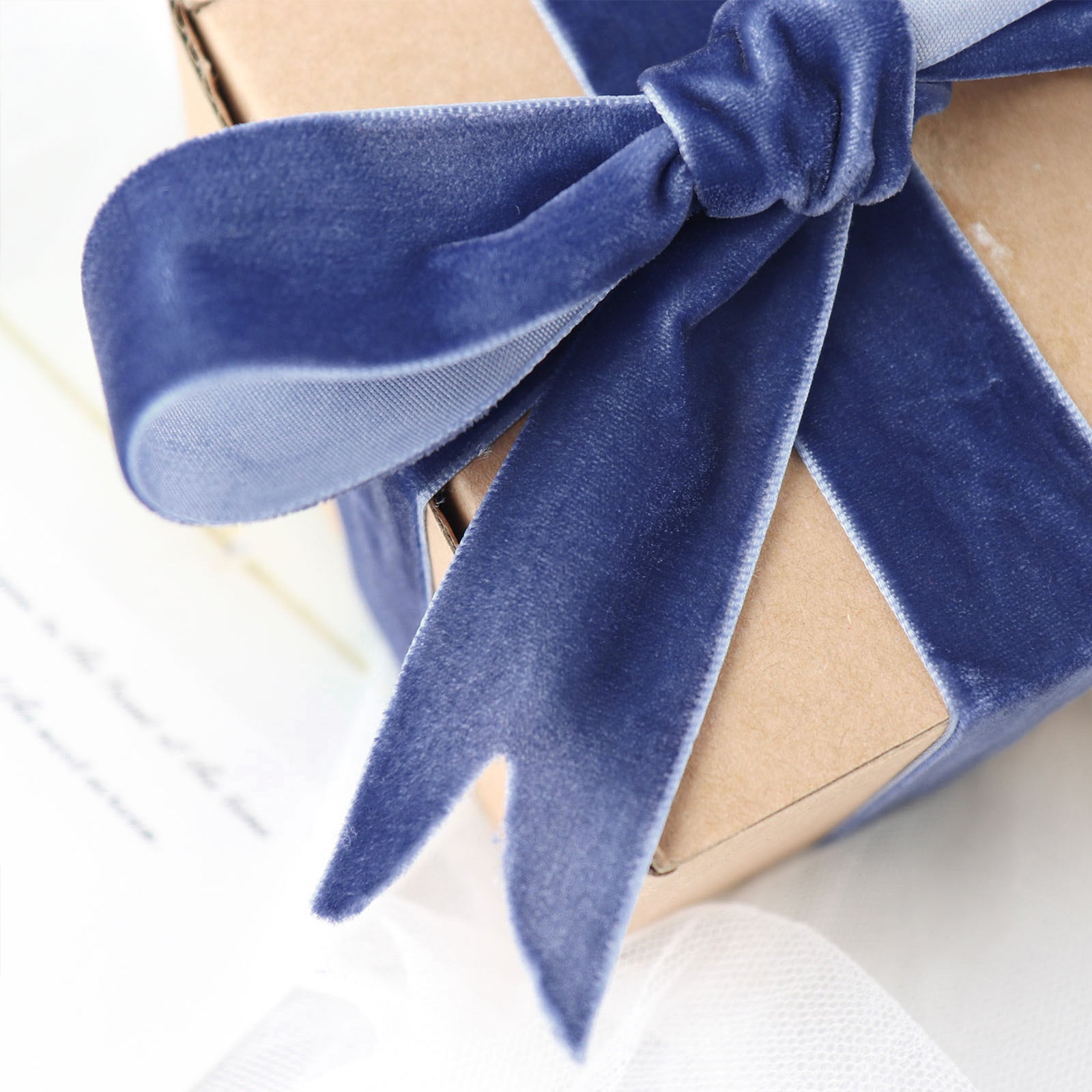 Navy blue velvet ribbon tied around a gift box.