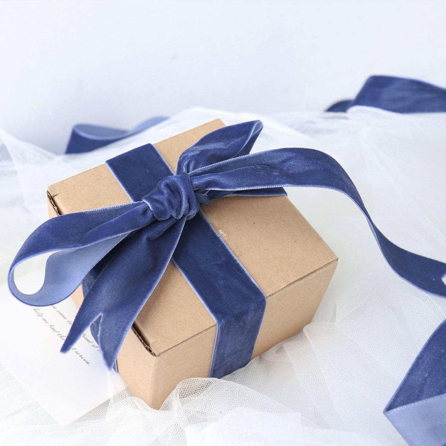 Navy blue velvet ribbon tied around a gift box on a soft background.