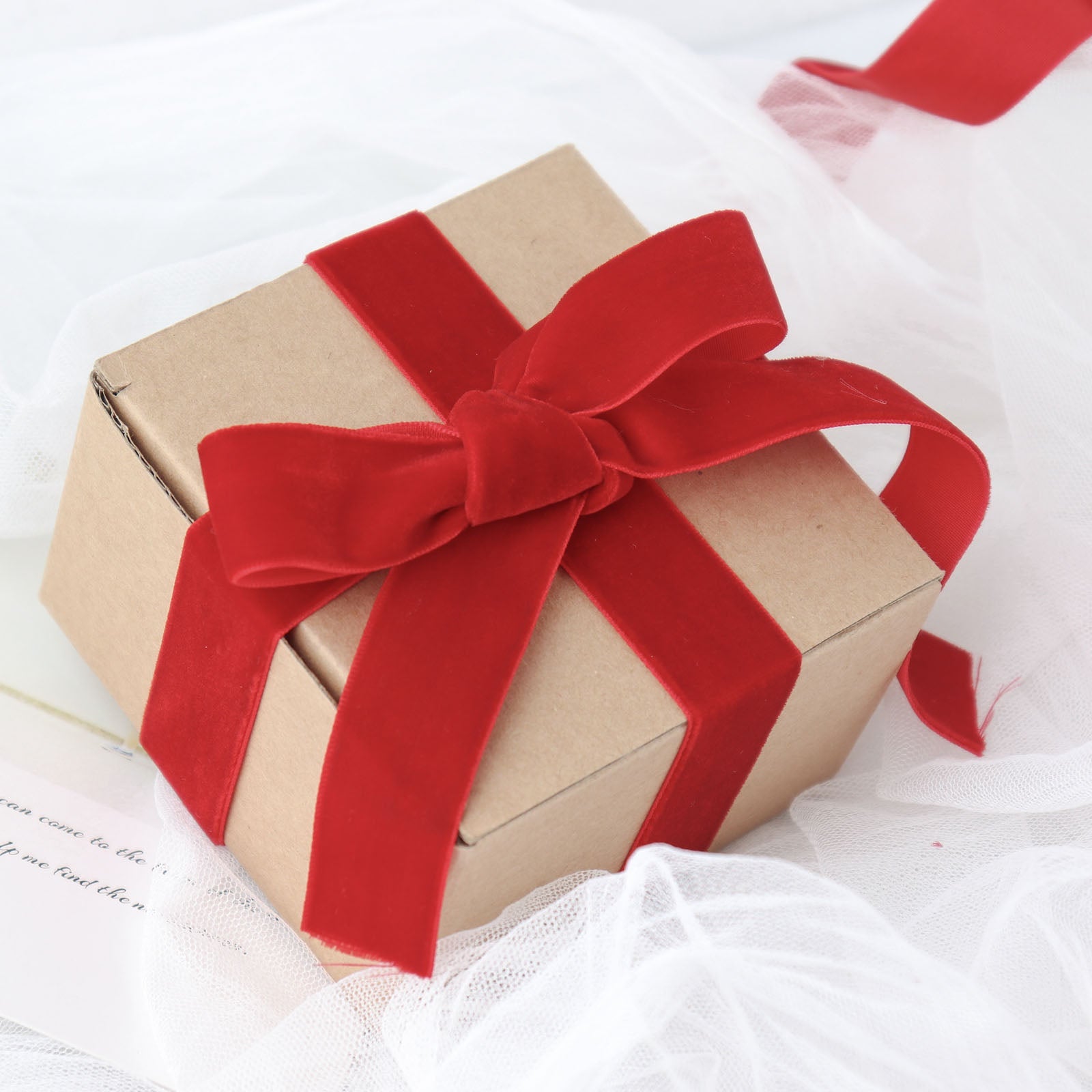 Red velvet ribbon spool on a gift box, perfect for DIY crafts.
