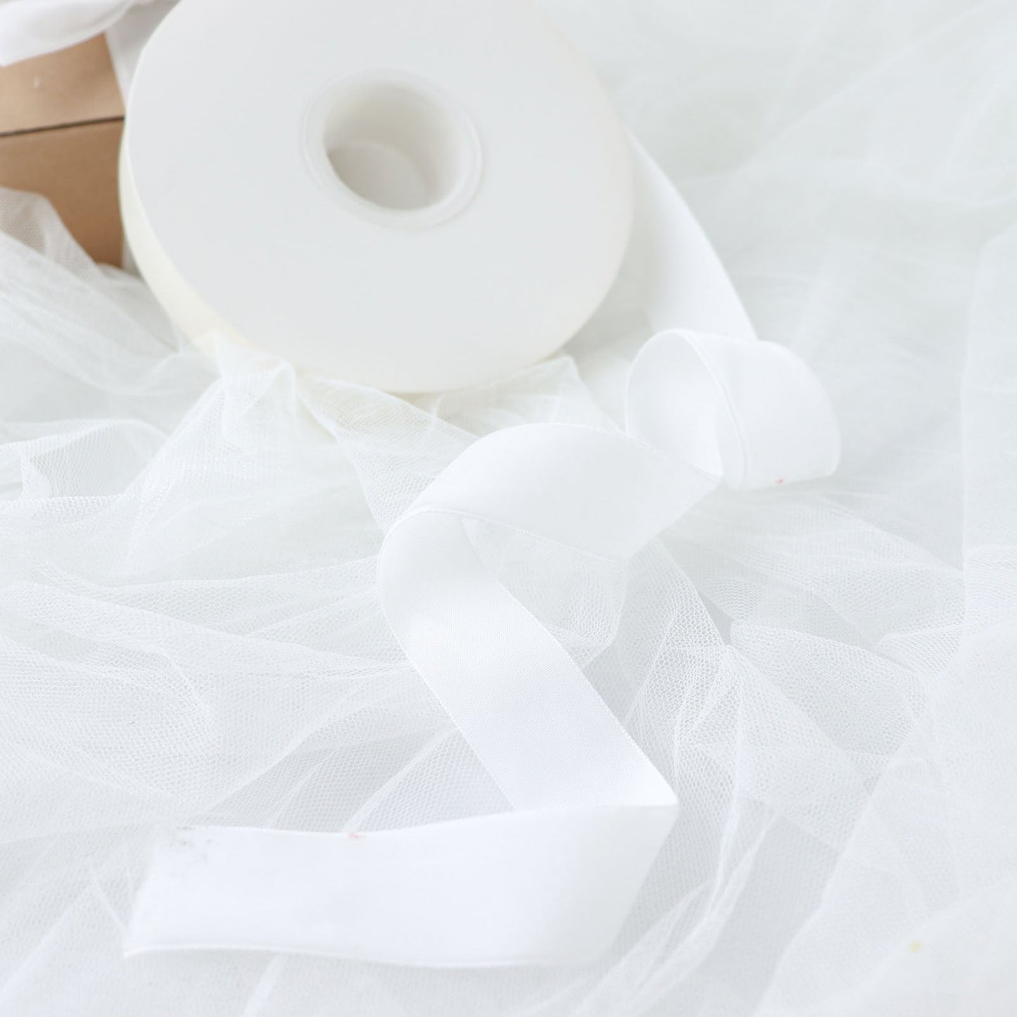 White velvet ribbon spool on a white fabric background.
