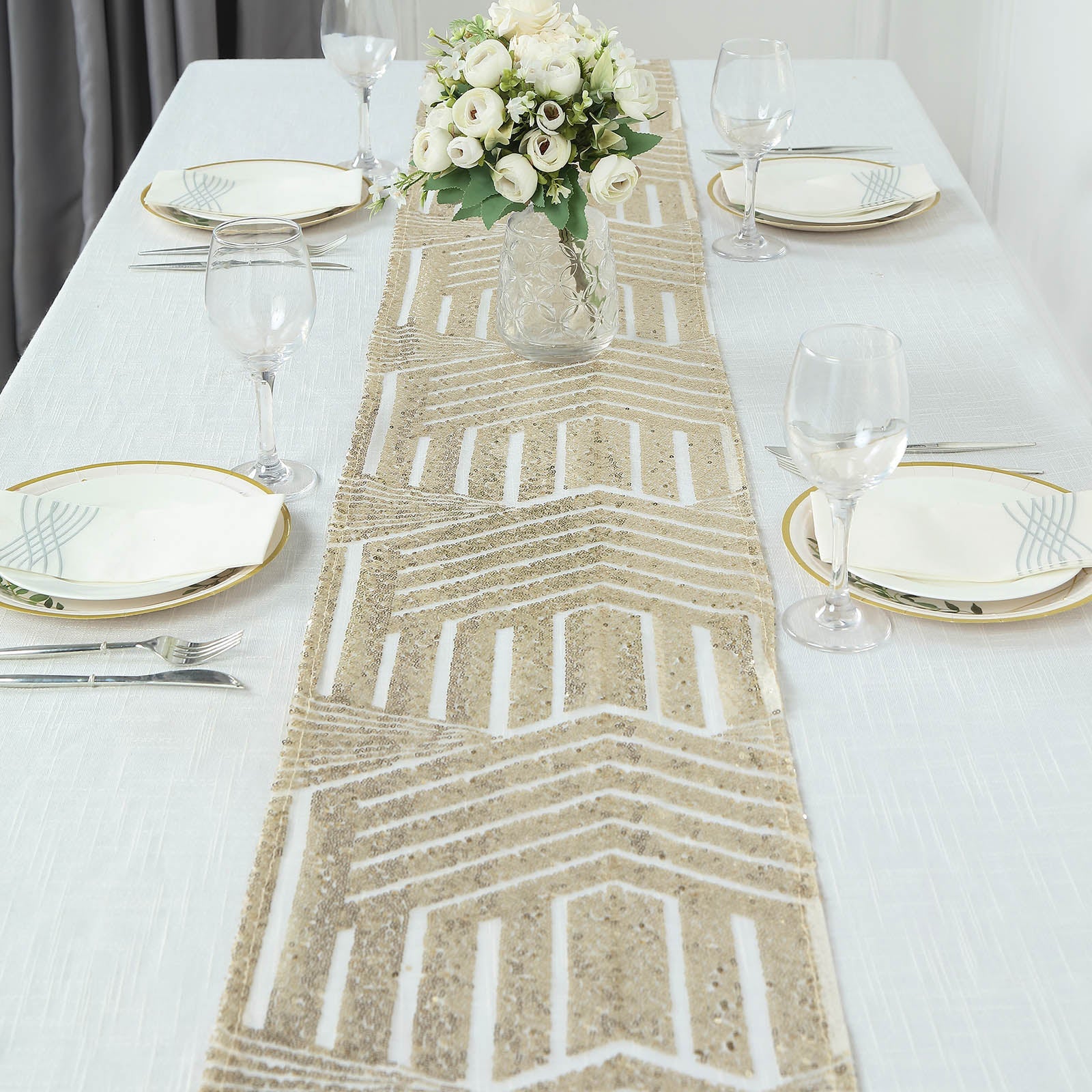 Champagne sequin table runner on a dining table with floral centerpiece.