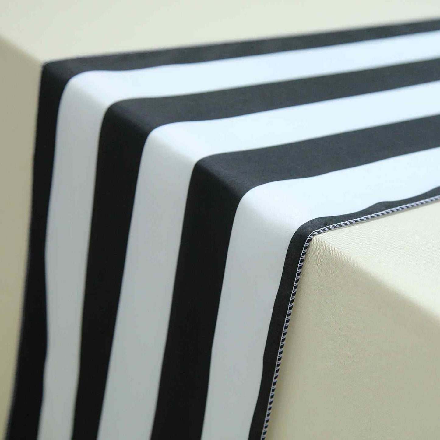 Black and white stripe satin table runner 12" x 108" on a light surface.
