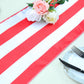 Red and white stripe satin table runner with floral arrangement.