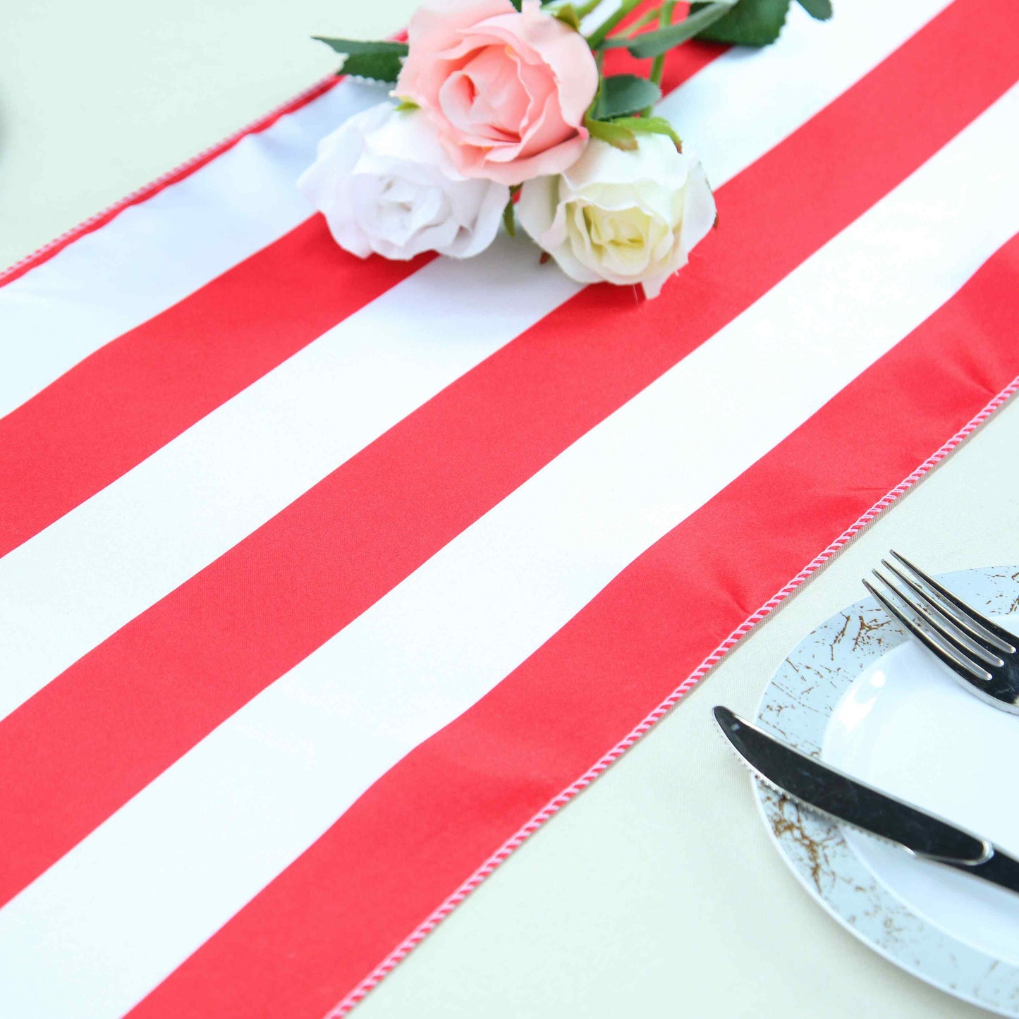 Red and white stripe satin table runner with floral arrangement.
