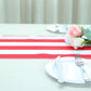 Red and white stripe satin table runner on a dining table with plates and flowers.