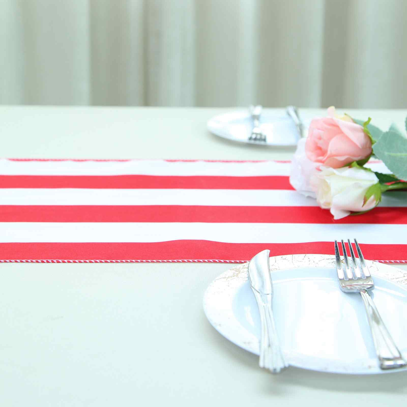 Red and white stripe satin table runner on a dining table with plates and flowers.