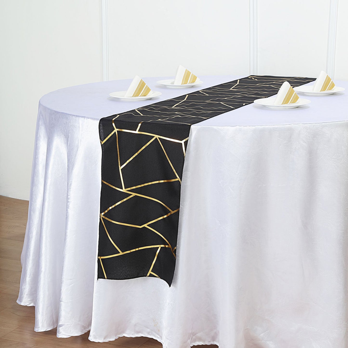 Black geometric pattern table runner with gold foil accents on a white table.