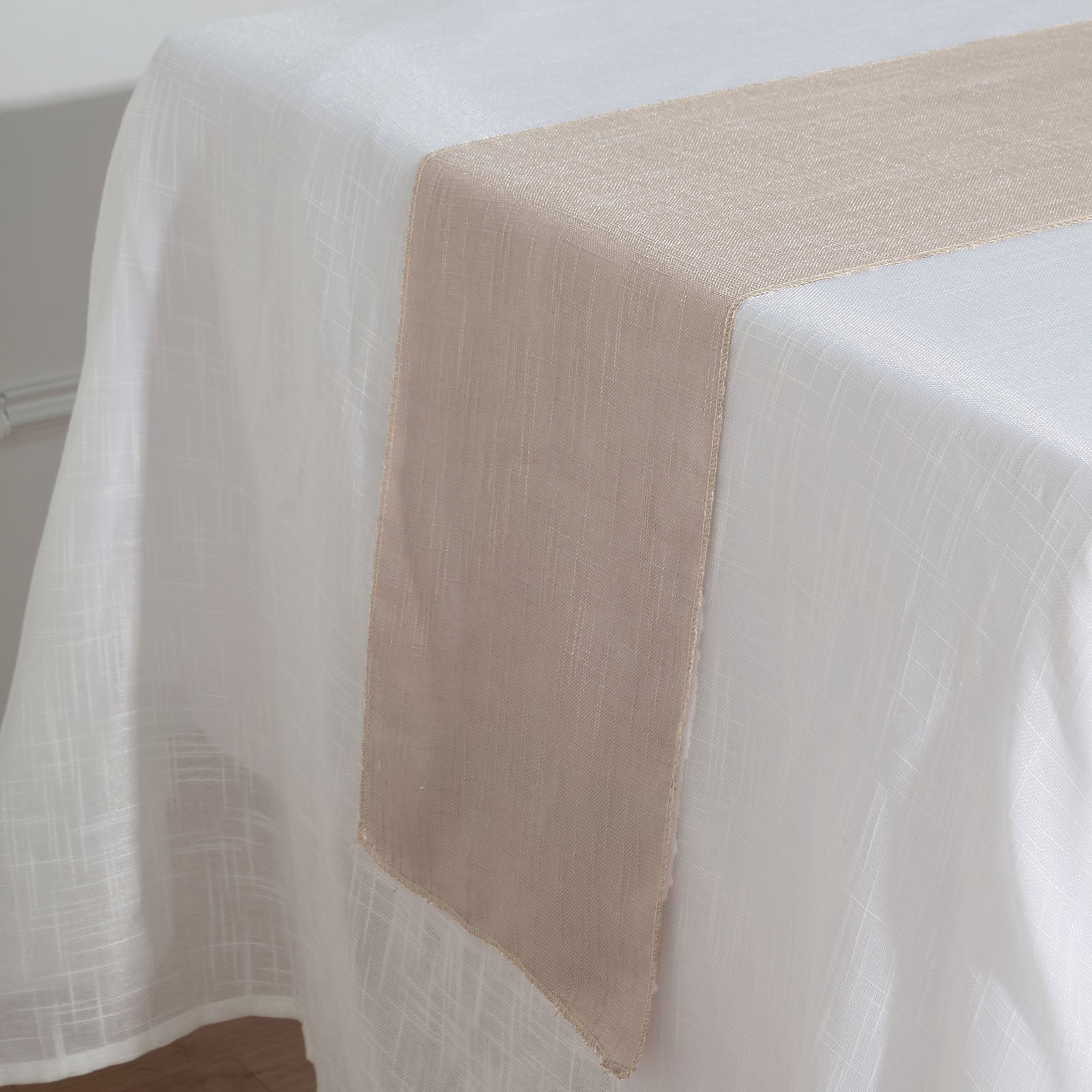 Taupe linen table runner on a white tablecloth.