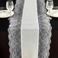 Ivory faux burlap jute table runner with white lace edging on a black table.