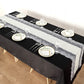 Ivory burlap table runner with white lace edging on a black table setting.